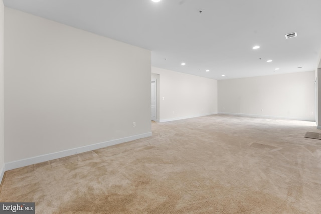 spare room featuring recessed lighting, light carpet, and baseboards