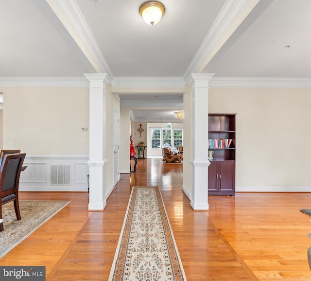 entrance foyer featuring ornate columns, crown molding, and light wood finished floors