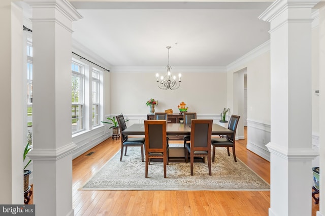 dining room with decorative columns, light wood-type flooring, a chandelier, and crown molding