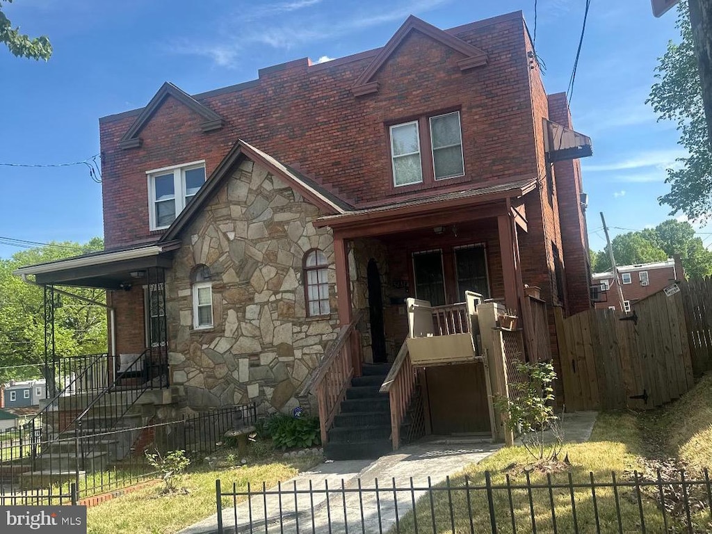 view of front of property with stone siding, brick siding, and a fenced front yard