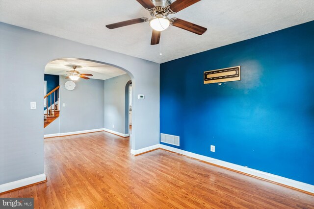 5218 Arbutus Ave, Baltimore, MD 21227 - empty room featuring a ceiling fan, arched walkways, wood finished floors, and stairway