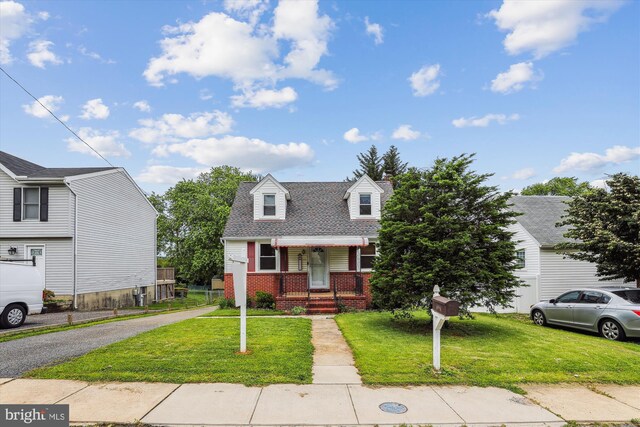 5218 Arbutus Ave, Baltimore, MD 21227 - view of front of house with a front yard, brick siding, a porch, and driveway