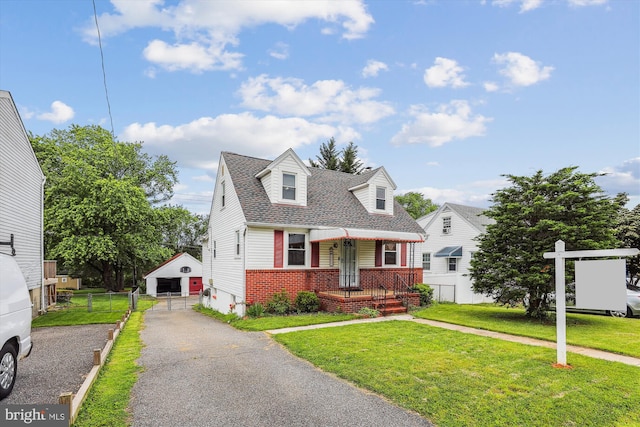 5218 Arbutus Ave, Baltimore, MD 21227 - new england style home featuring brick siding, an outdoor structure, a shingled roof, and asphalt driveway
