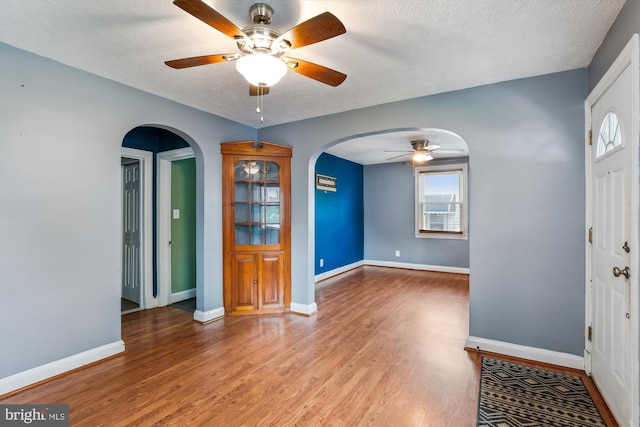 5218 Arbutus Ave, Baltimore, MD 21227 - foyer entrance featuring a ceiling fan, arched walkways, wood finished floors, plenty of natural light, and a textured ceiling