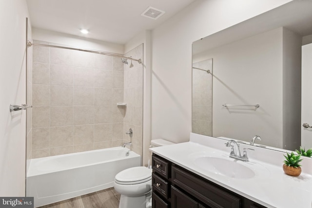 full bath with vanity, toilet, wood finished floors, shower / bathing tub combination, and visible vents