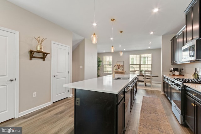 kitchen with light countertops, appliances with stainless steel finishes, a sink, and light wood-style floors