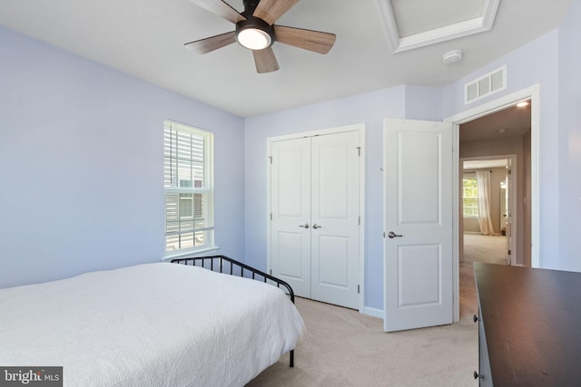bedroom featuring ceiling fan, light colored carpet, baseboards, visible vents, and a closet