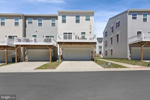 view of property featuring a garage, central air condition unit, and concrete driveway