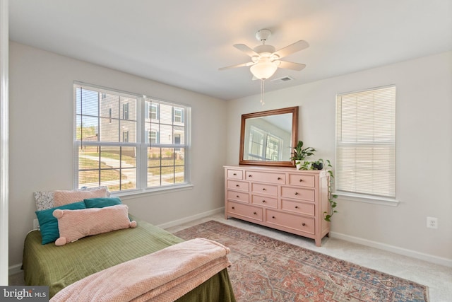 bedroom with baseboards, a ceiling fan, visible vents, and light colored carpet