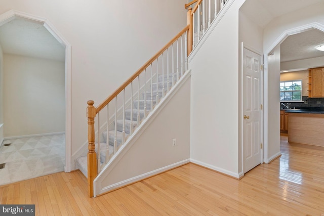 10413 Markby Ct, White Plains, MD 20695 - stairway with arched walkways, baseboards, and hardwood / wood-style flooring