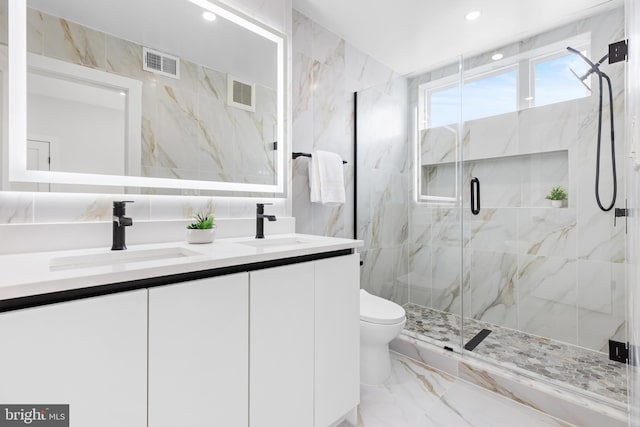 full bath featuring tile walls, toilet, marble tiled flooring, a marble finish shower, and double vanity