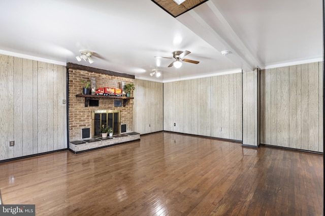 unfurnished living room featuring wooden walls, a fireplace, wood-type flooring, a ceiling fan, and visible vents