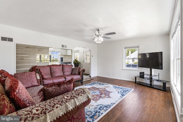 living room with arched walkways, a ceiling fan, wood finished floors, and visible vents