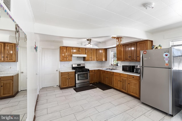 kitchen featuring appliances with stainless steel finishes, plenty of natural light, under cabinet range hood, and brown cabinets