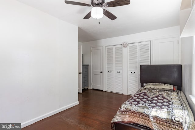 bedroom featuring baseboards, ceiling fan, two closets, and wood finished floors
