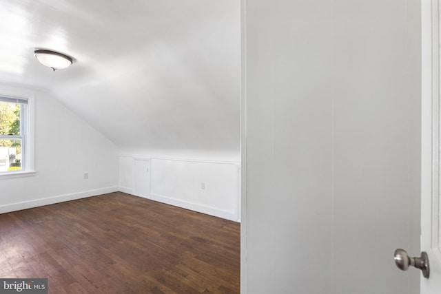 bonus room with baseboards, vaulted ceiling, and dark wood-style floors