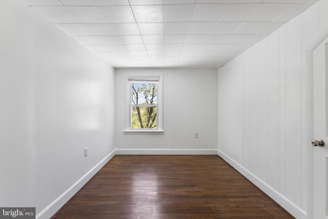unfurnished room with baseboards and dark wood finished floors