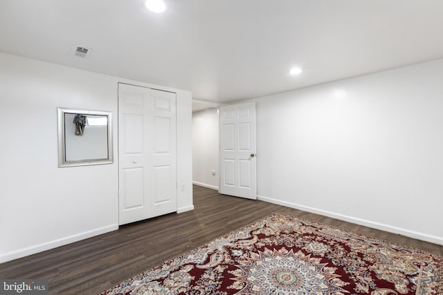 finished below grade area with recessed lighting, baseboards, visible vents, and dark wood-style floors