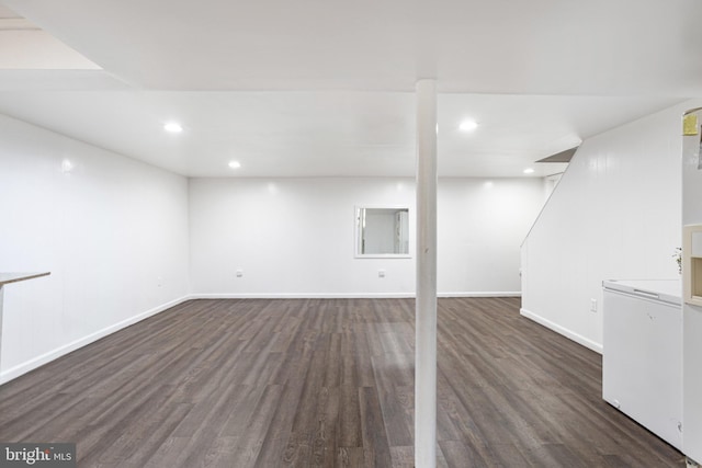 finished below grade area with recessed lighting, baseboards, dark wood-style floors, and fridge
