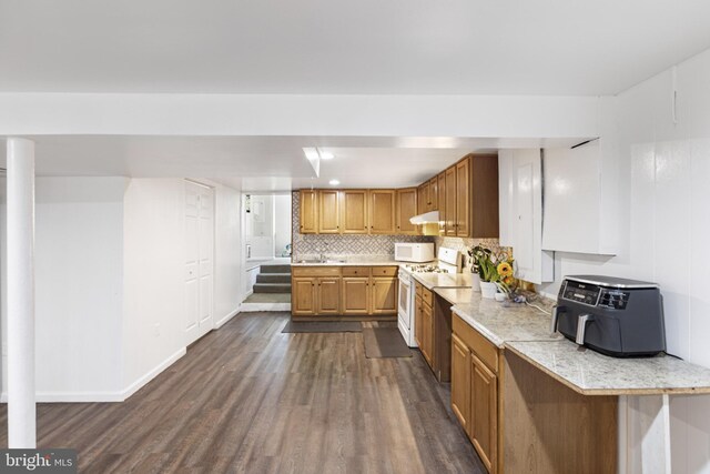 kitchen featuring dark wood-type flooring, light countertops, under cabinet range hood, and white appliances