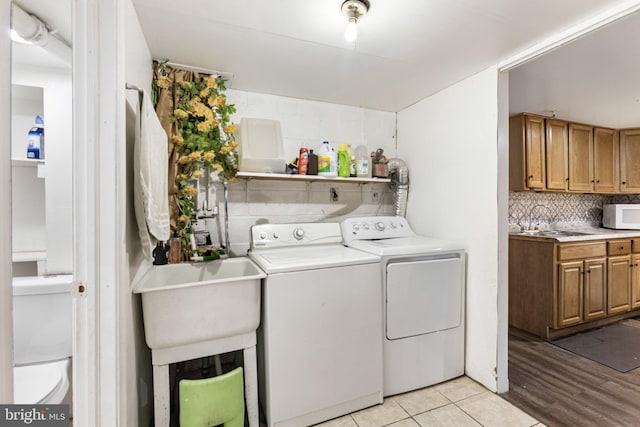 laundry area with a sink, light tile patterned floors, and washing machine and dryer