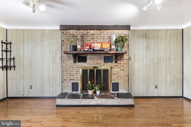 living area with a ceiling fan, wood walls, and wood finished floors