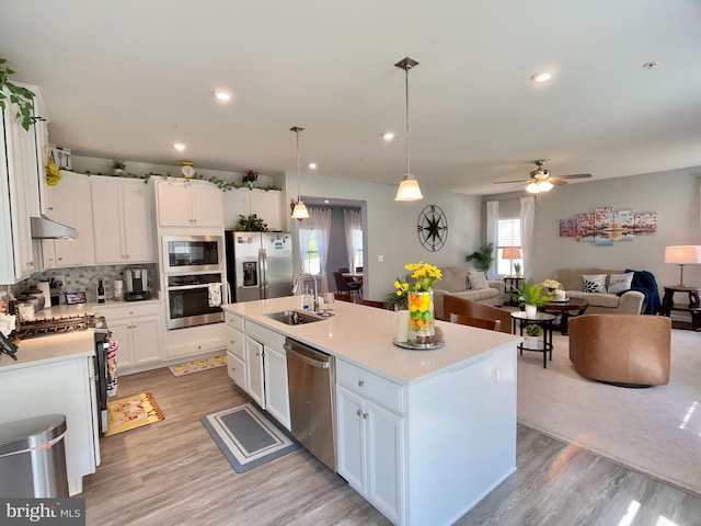 kitchen with a sink, light wood-style floors, light countertops, white cabinets, and appliances with stainless steel finishes