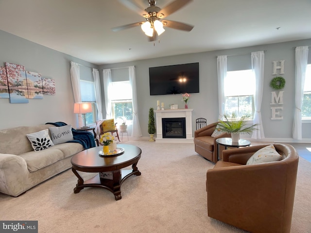 carpeted living area featuring a glass covered fireplace, ceiling fan, and plenty of natural light