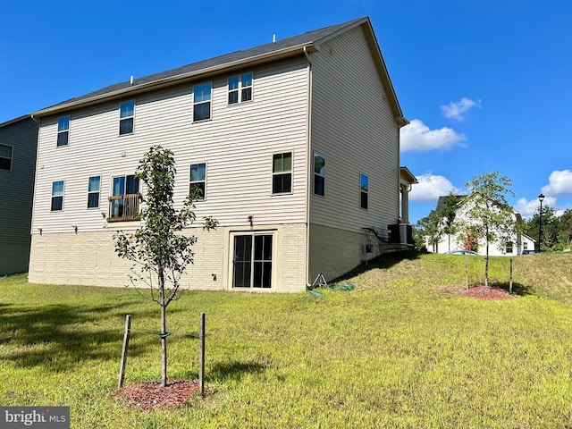 back of house with a lawn, central AC unit, and brick siding