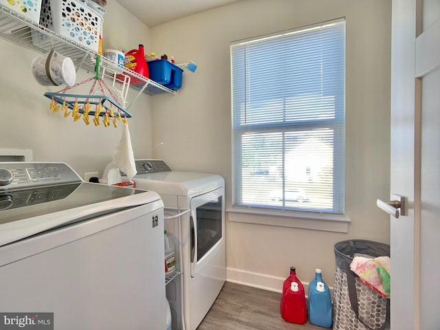 clothes washing area featuring wood finished floors, baseboards, laundry area, and washing machine and dryer