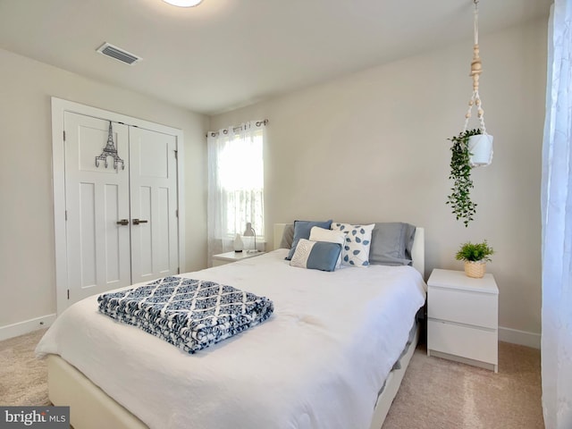 bedroom featuring a closet, visible vents, light colored carpet, and baseboards