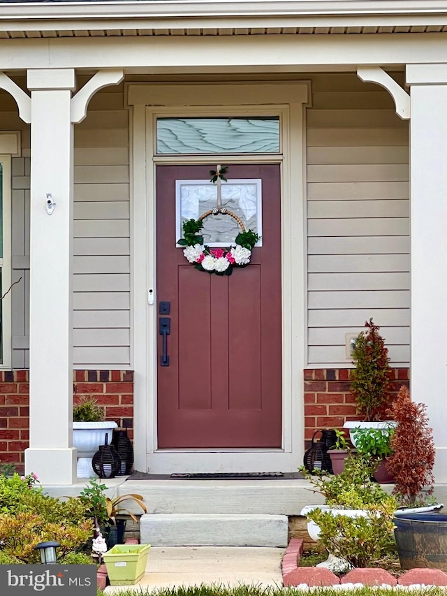 entrance to property with a porch and brick siding