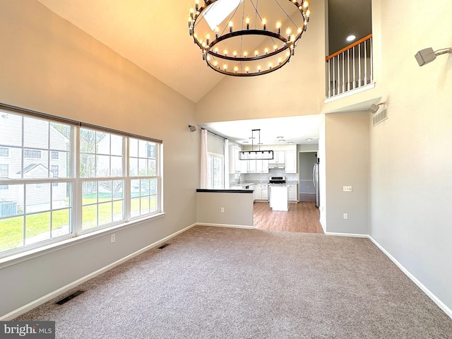 1 Donegal, Newark, DE 19702 - unfurnished living room with visible vents, a notable chandelier, light colored carpet, and high vaulted ceiling