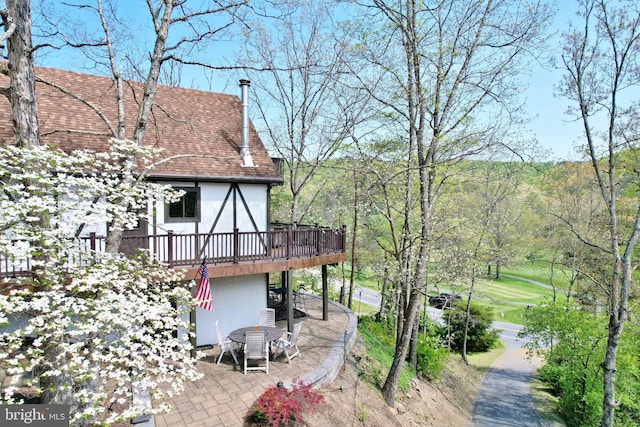 back of property featuring a shingled roof, a patio area, stucco siding, and a deck