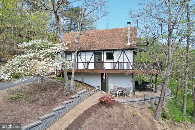 back of house featuring a patio, roof with shingles, a wooden deck, and stucco siding
