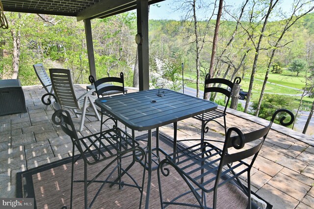 view of patio with outdoor dining area and a forest view