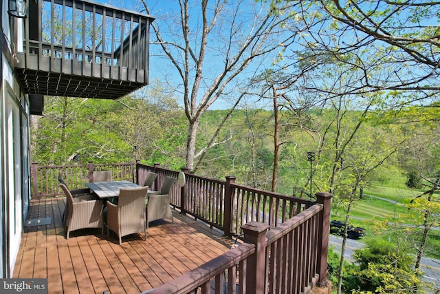 deck with outdoor dining area and a view of trees