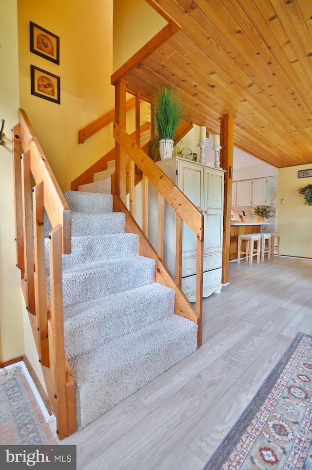 stairs with wooden ceiling, baseboards, wood finished floors, and lofted ceiling