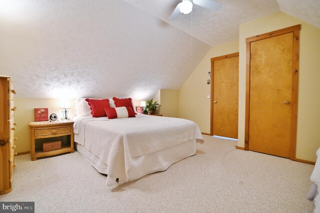bedroom with a textured ceiling, vaulted ceiling, baseboards, and carpet
