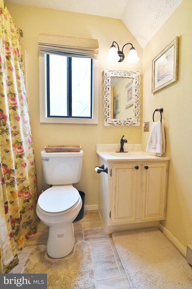 full bath with baseboards, tile patterned floors, vanity, toilet, and lofted ceiling