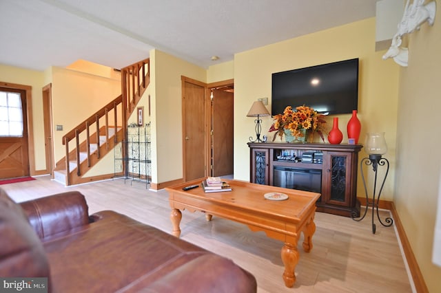 living room featuring baseboards, wood finished floors, and stairway
