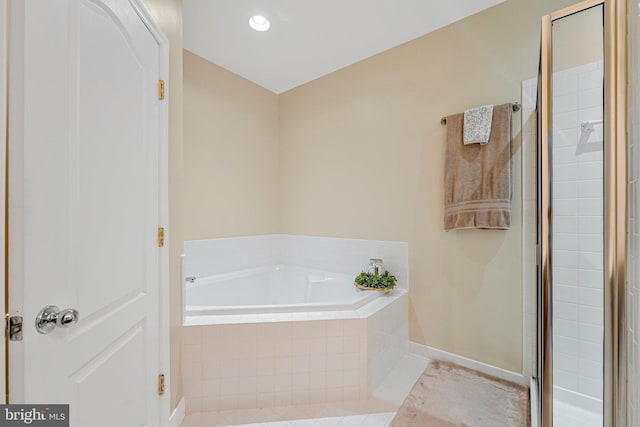full bath featuring a garden tub, a shower stall, and baseboards