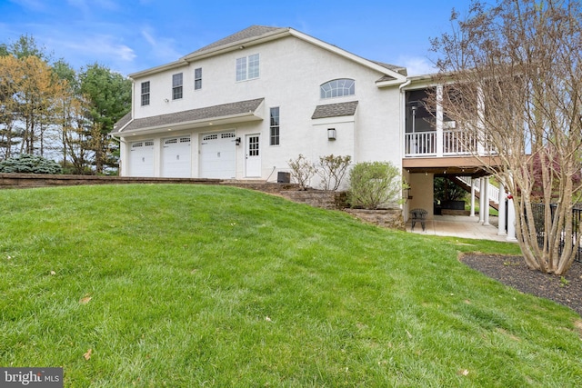 back of house featuring a lawn, a patio, an attached garage, and stucco siding