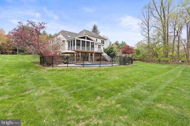 back of house with fence, a yard, a fenced in pool, and a sunroom