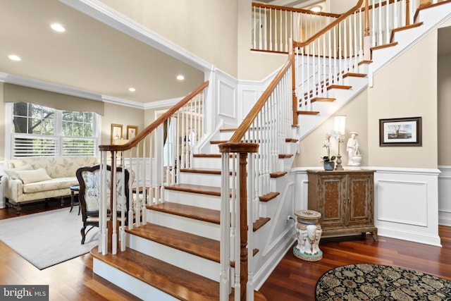 stairway featuring crown molding, recessed lighting, wood finished floors, and a decorative wall