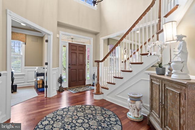 entryway with plenty of natural light, a wainscoted wall, a decorative wall, and wood finished floors