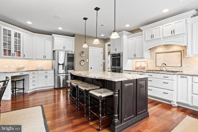 kitchen featuring white cabinetry, appliances with stainless steel finishes, a kitchen island, and tasteful backsplash