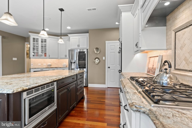 kitchen with decorative backsplash, stainless steel appliances, white cabinetry, and visible vents