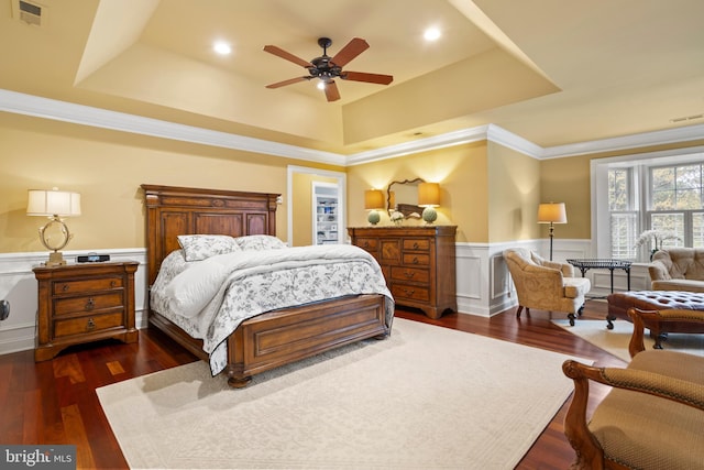 bedroom with a raised ceiling, a wainscoted wall, dark wood-type flooring, and visible vents