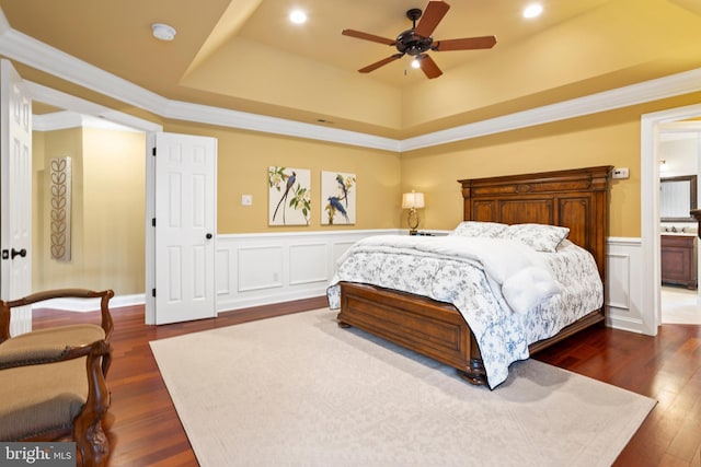 bedroom featuring wainscoting, a raised ceiling, and dark wood-type flooring